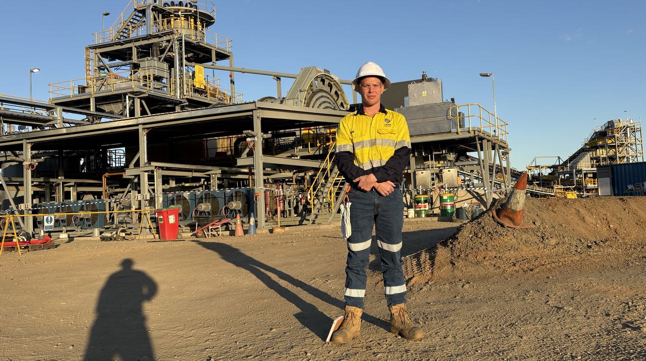 A Lean Mining team member on site in front of a mineral processing plant at sunset.