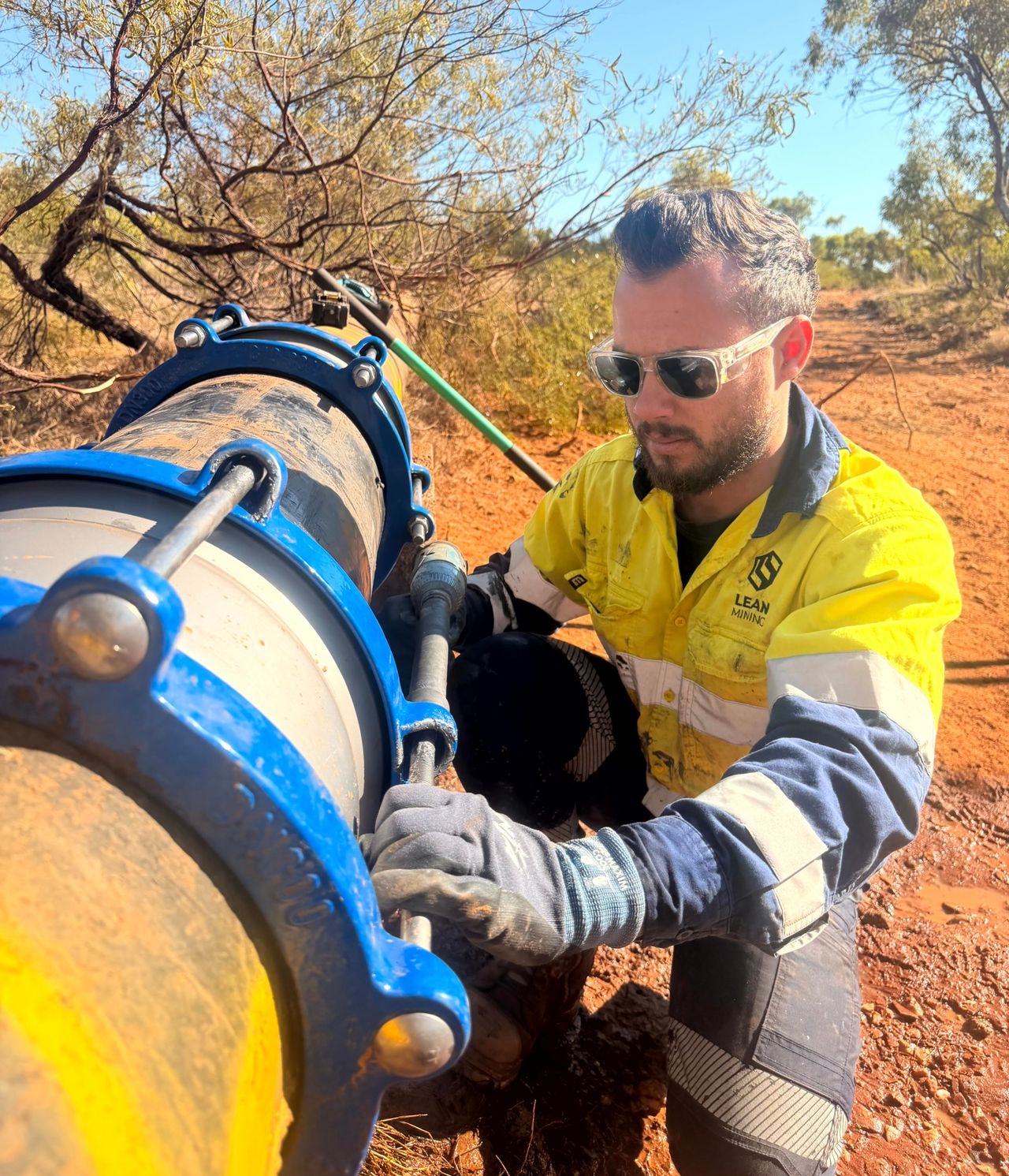 A Lean Mining tradesperson tensioning a flange coupling on a pipeline in the field.